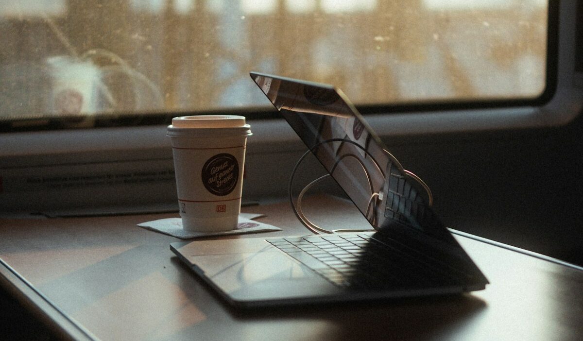 Senior ad-tech specialist optimizing PMP floors on NJ Transit sunrise commute, laptop open, coffee in hand, boosting publisher eCPM before NYC market opens